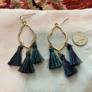 Gold dangly earrings with green and purple fringe.